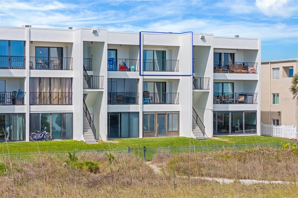 A three-story apartment building features balconies and sliding glass doors facing a grassy lawn — 829 1ST STREET S UNIT 3B, JACKSONVILLE BEACH, FL