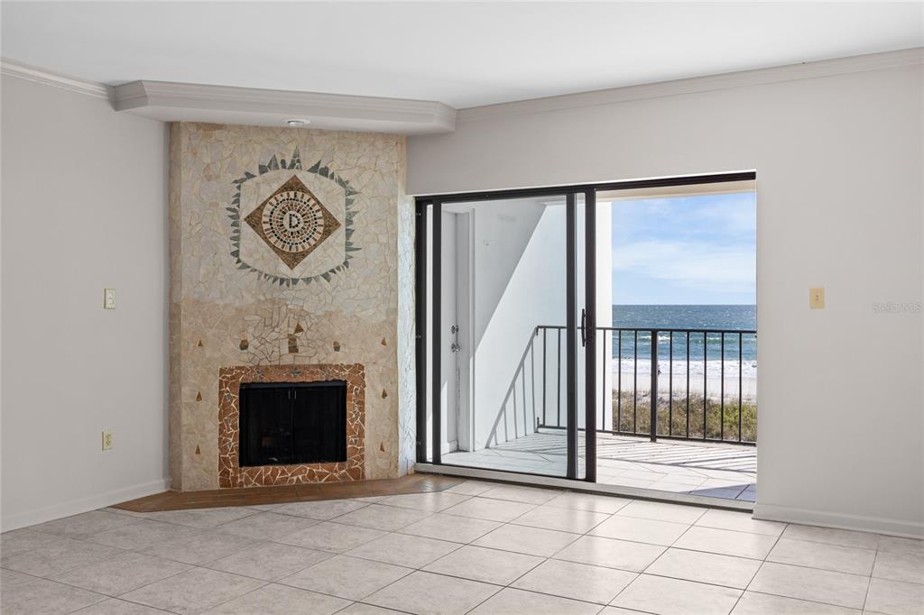 A living room with a tiled fireplace and sliding glass doors opening to a beach view — 829 1ST STREET S UNIT 3B, JACKSONVILLE BEACH, FL