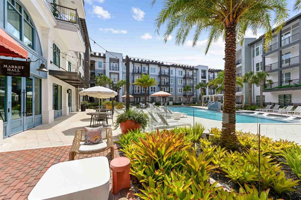 An outdoor pool area with lounge chairs, palm trees, and a building labeled Market Hall — 1464 LAUREL SOUND LANE UNIT C1, SANFORD, FL