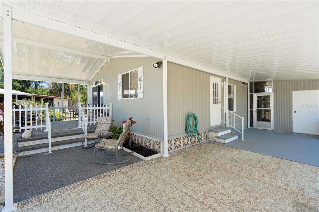 A mobile home exterior featuring a covered carport, a small patio, and a white fence — 925 IGLESIA DRIVE, NORTH PORT, FL