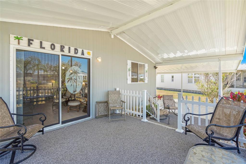 A covered patio features a sliding glass door, outdoor furniture, and a white picket fence — 925 IGLESIA DRIVE, NORTH PORT, FL