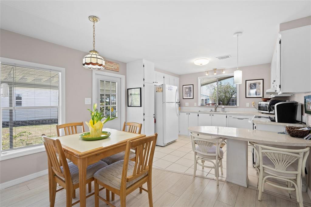 A kitchen and dining area with light wood flooring, white cabinets, and a dining table — 925 IGLESIA DRIVE, NORTH PORT, FL