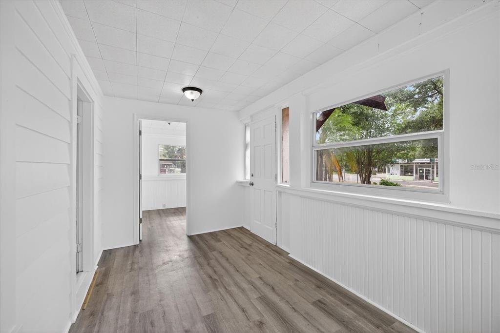 A sunroom features white beadboard walls, a tiled ceiling, and wood-look flooring — 2211 22ND AVENUE S, ST PETERSBURG, FL