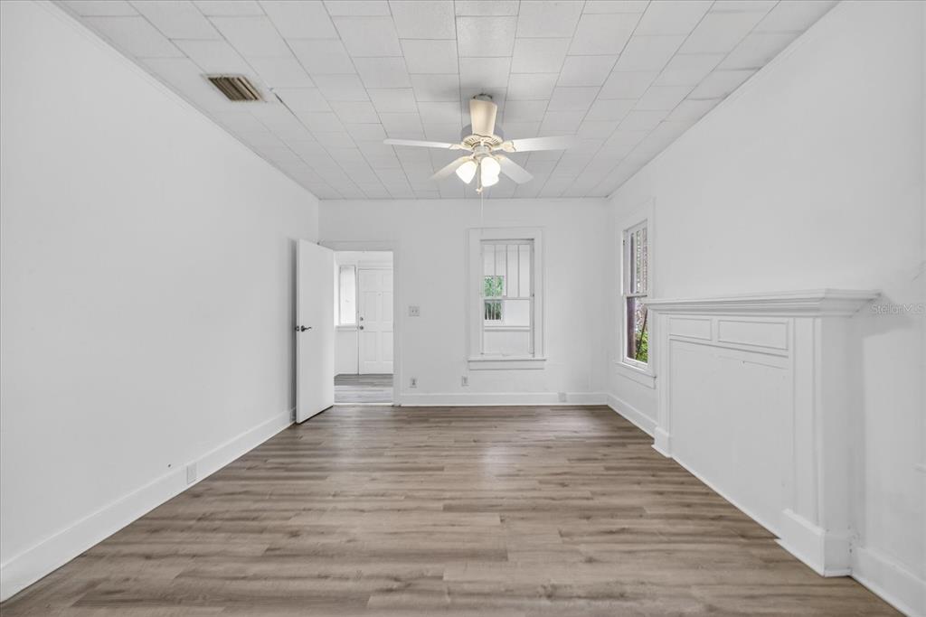 A white room features wood-look flooring, a ceiling fan, and a fireplace mantle — 2211 22ND AVENUE S, ST PETERSBURG, FL