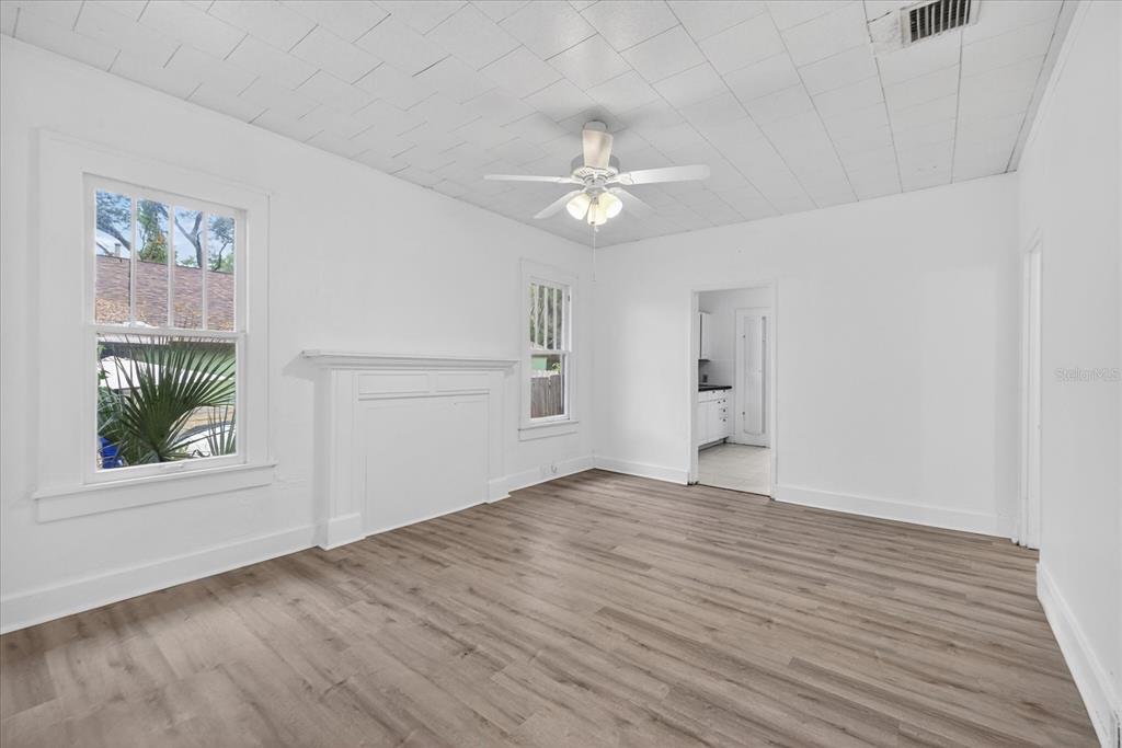A bright room features white walls, light wood-look flooring, a fireplace mantel, and a ceiling fan — 2211 22ND AVENUE S, ST PETERSBURG, FL