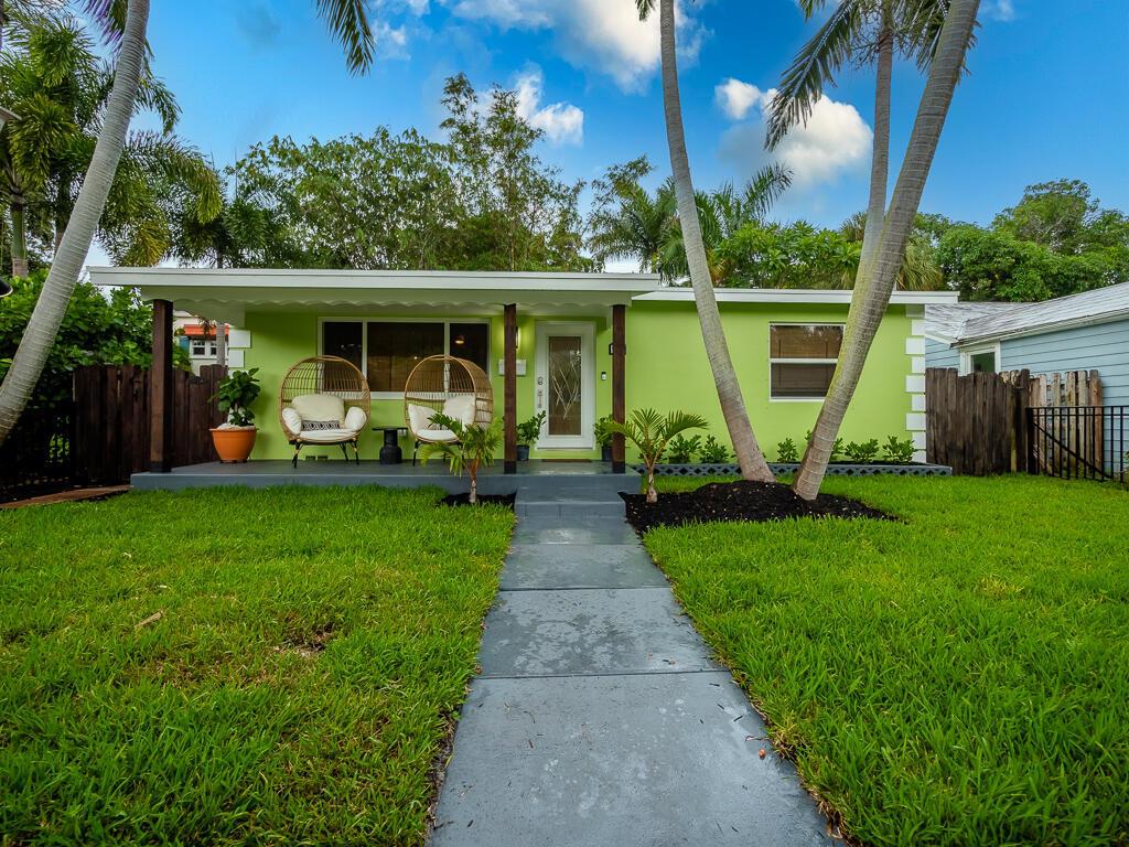A lime green house with a covered front porch, two hanging chairs, and palm trees — 418 N Palmway, FL 33460, FL