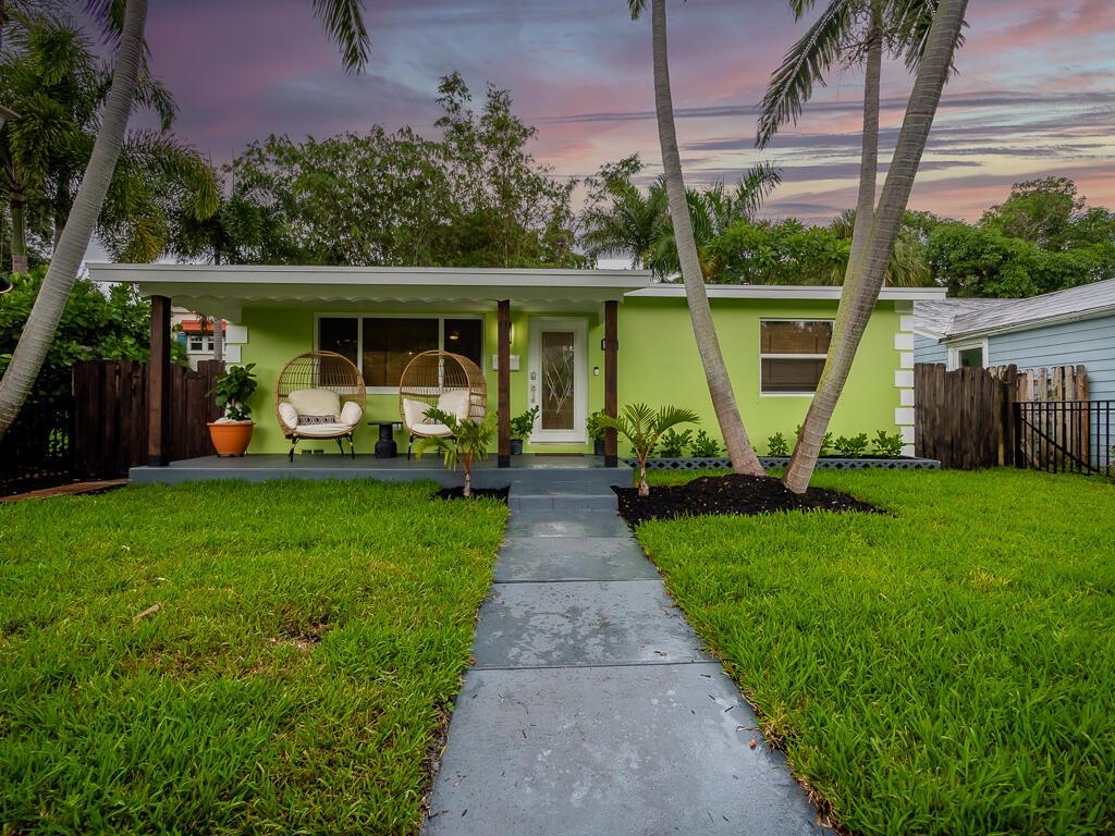 A lime green house with a covered front porch, two wicker chairs, and palm trees — 418 N Palmway, FL 33460, FL
