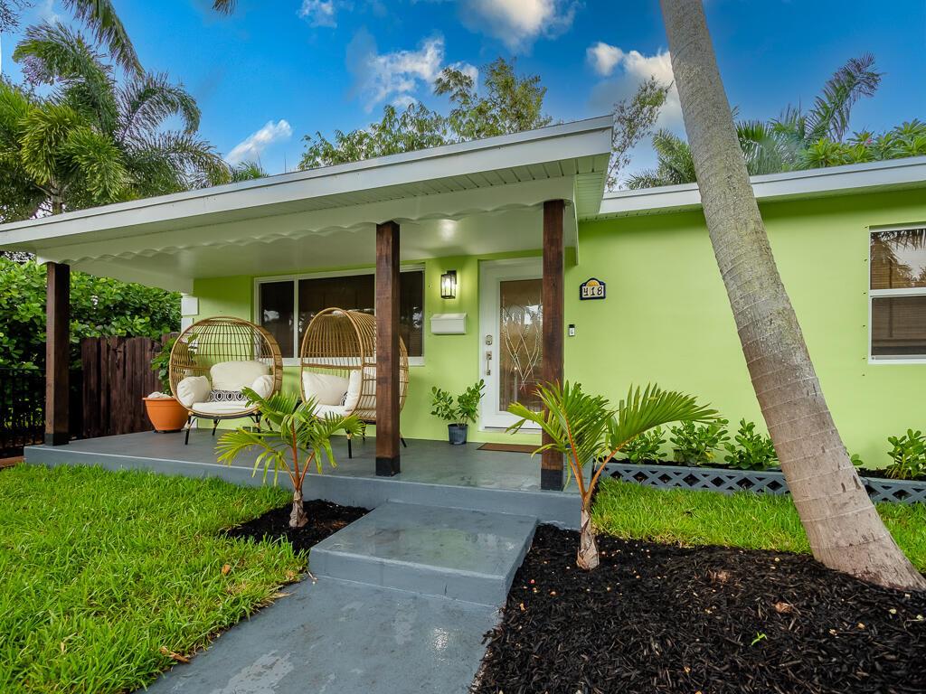 A light green house features a covered front porch with two wicker chairs and palm trees — 418 N Palmway, FL 33460, FL