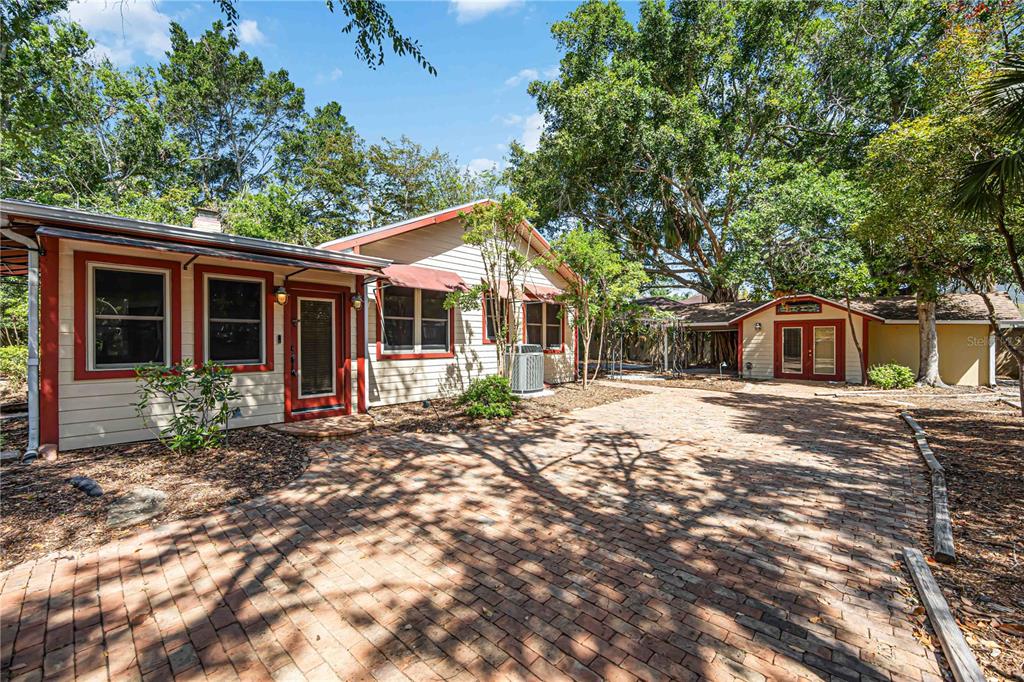 A brick patio leads to a single-story house with tan siding and red trim — 1743 8TH STREET, SARASOTA, FL