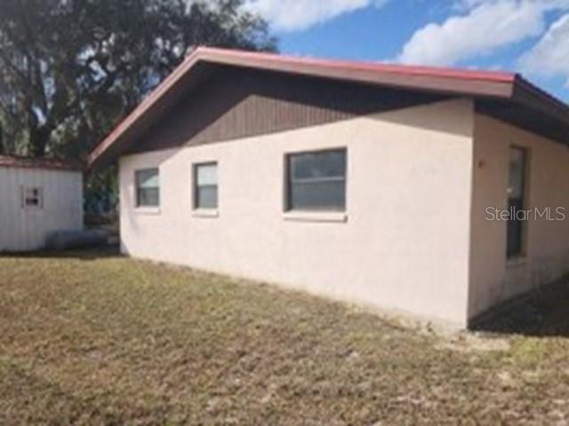 The exterior of a single-story house with beige stucco walls and a red roof — 5875 NE 167TH AVENUE, SILVER SPRINGS, FL