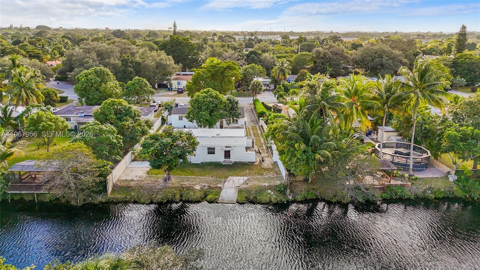 An aerial view shows a white house with a flat roof situated along a canal — 201 S Biscayne River Dr, Miami FL 33169, MIAMI, FL