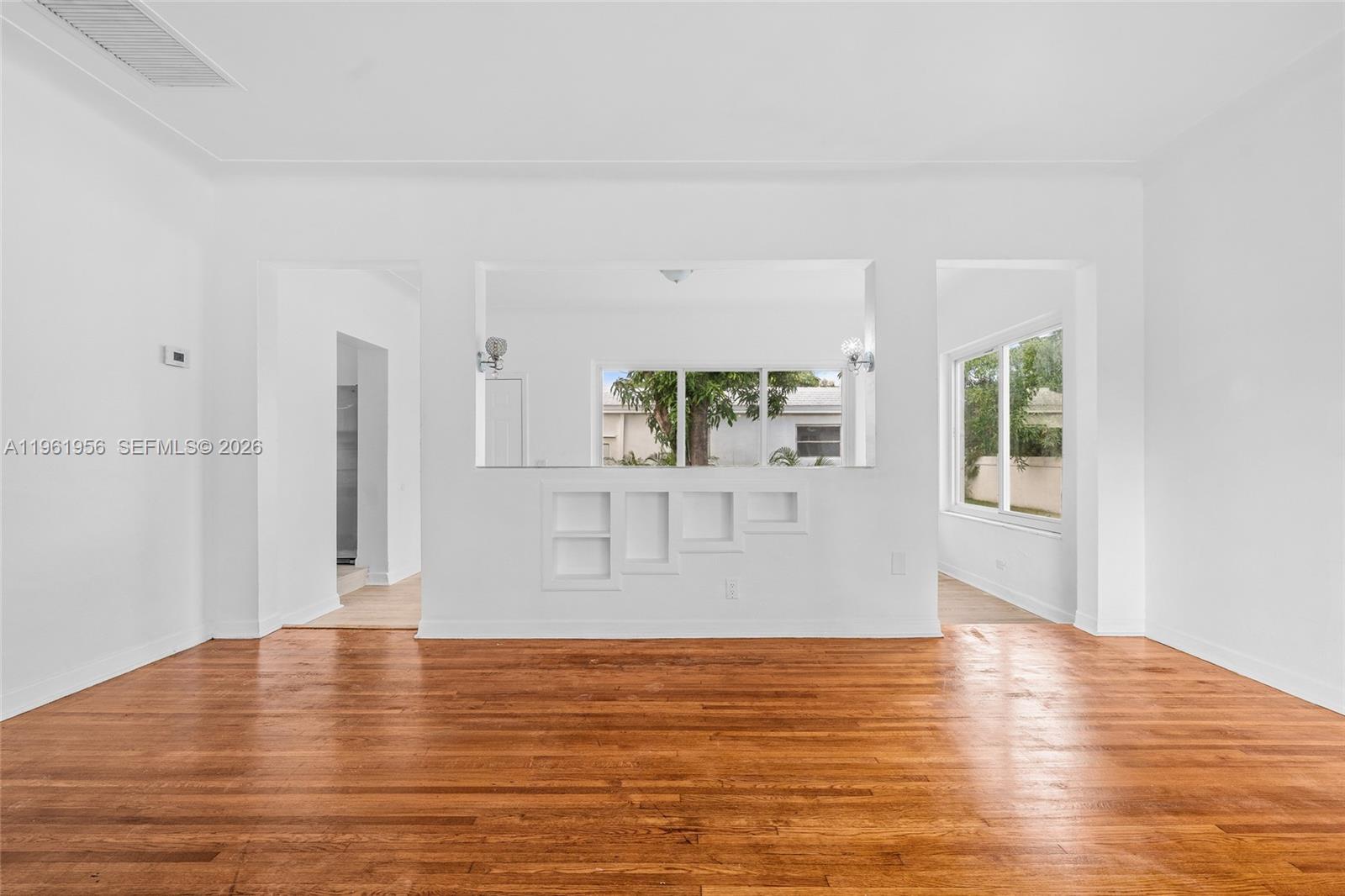 A living room features hardwood floors, white walls, and a pass-through window to another room — 201 S Biscayne River Dr, Miami FL 33169, MIAMI, FL