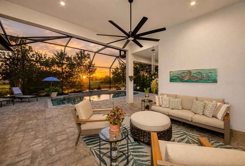 A covered patio features a seating area, a ceiling fan, and a pool with sunset views — 4657 ANTRIM DRIVE, SARASOTA, FL