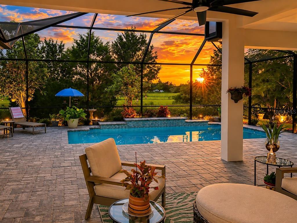 A covered patio with a pool, lounge chairs, and a sunset view through a screen enclosure — 4657 ANTRIM DRIVE, SARASOTA, FL