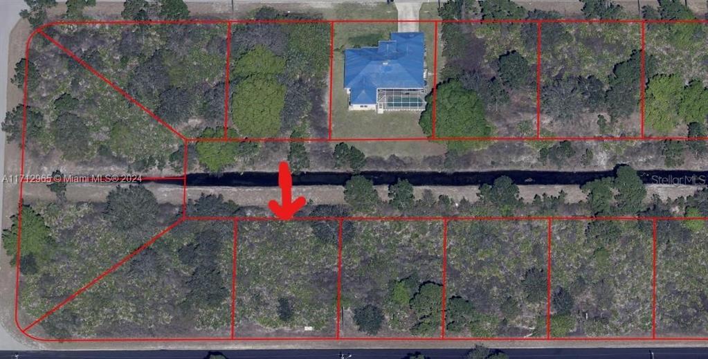 This aerial map shows a vacant residential lot marked with a red arrow — 1219 EDGEWOOD STREET E, LEHIGH ACRES, FL