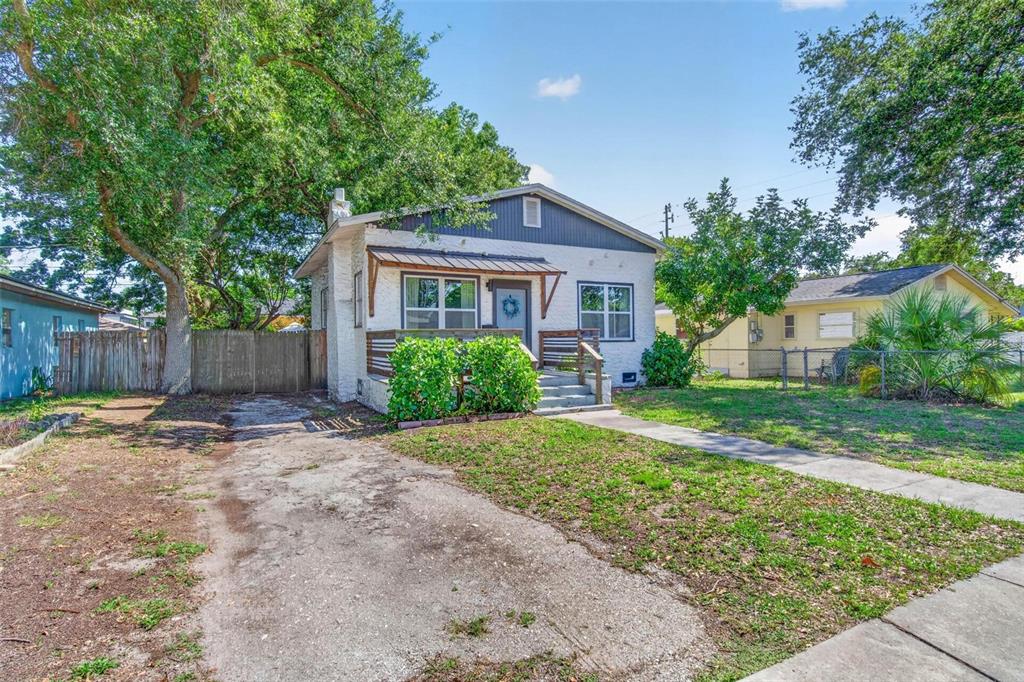 A white, single-story house with a front porch, a concrete driveway, and a grassy yard — 4556 YARMOUTH AVENUE S, ST PETERSBURG, FL