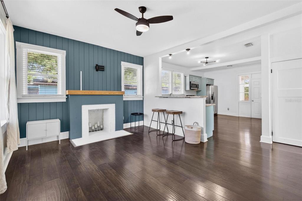 A living room with a blue accent wall, fireplace, and an open kitchen with bar seating — 4556 YARMOUTH AVENUE S, ST PETERSBURG, FL