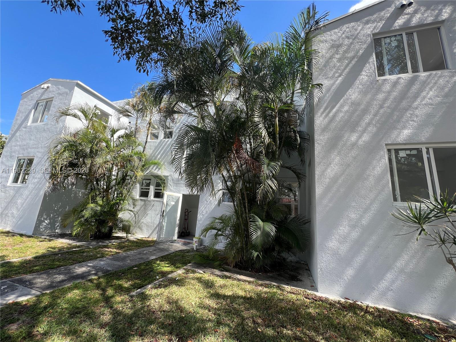 The exterior of a white multi-story building features palm trees and a concrete walkway — 1015 S 17th Ave # 9, Hollywood FL 33020, HOLLYWOOD, FL