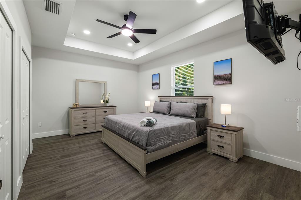 A bedroom features a tray ceiling, wood-look flooring, a bed, a dresser, and a nightstand — 174-176 S LEMON AVENUE, BROOKSVILLE, FL