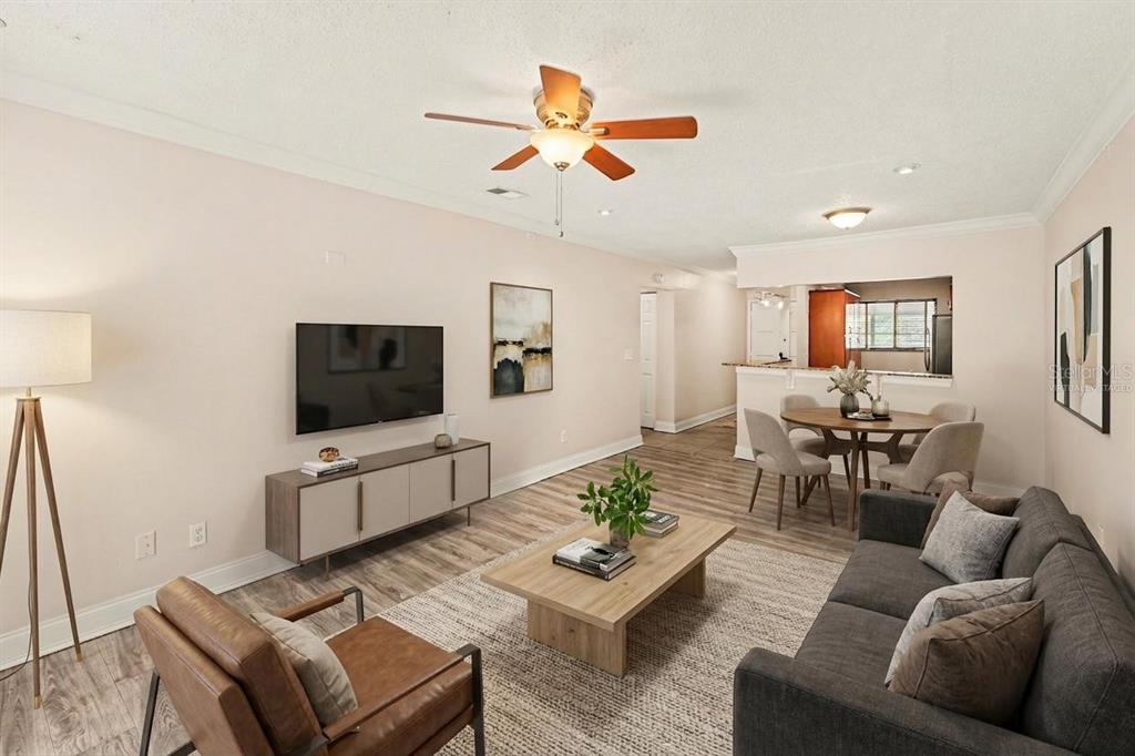 A living room with wood-look flooring, a ceiling fan, a television, and a dining area — 6334 NEWTOWN CIRCLE UNIT 34B3, TAMPA, FL