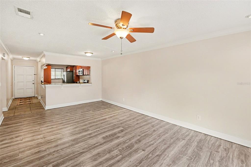 A living room with wood-look flooring, a ceiling fan, and an open kitchen pass-through — 6334 NEWTOWN CIRCLE UNIT 34B3, TAMPA, FL