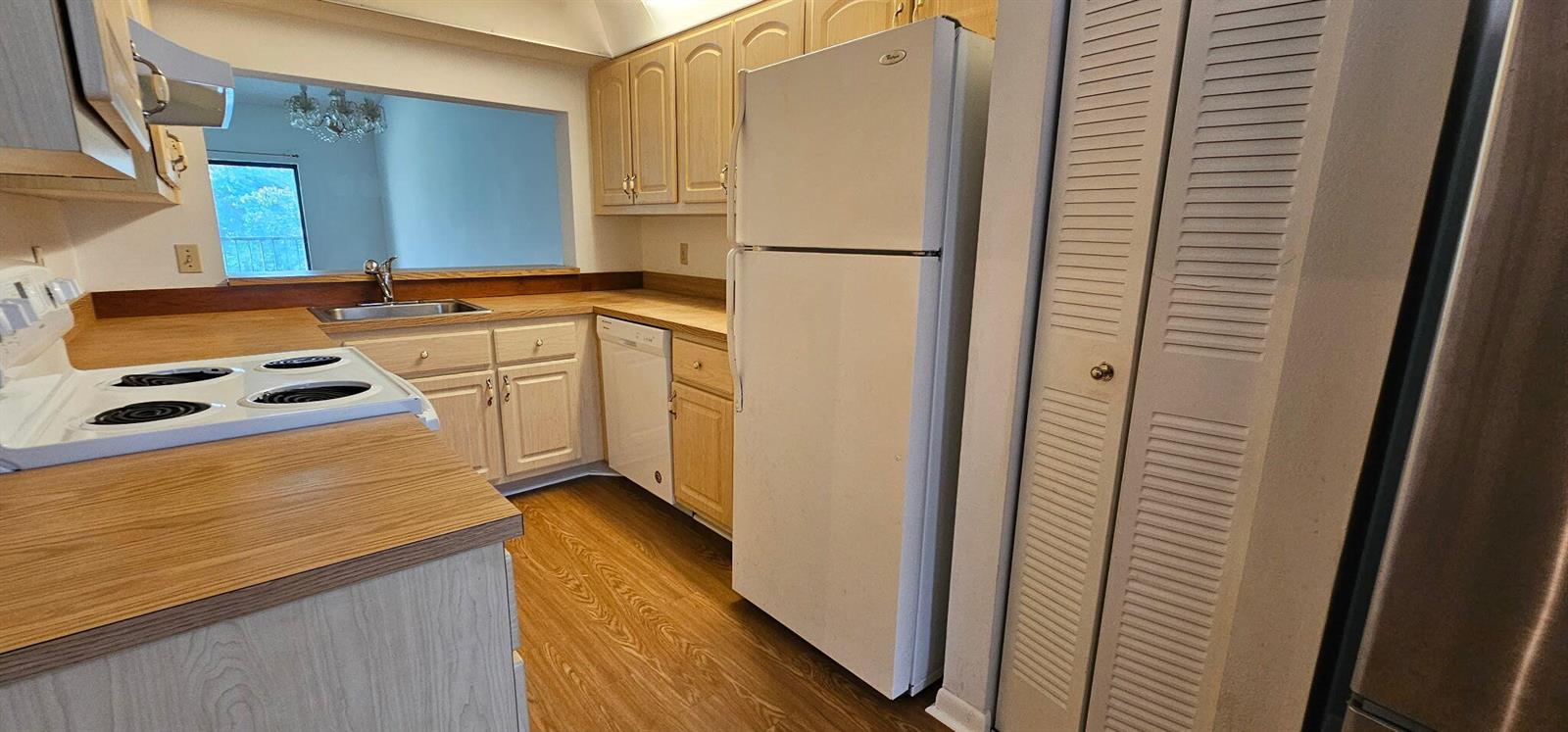 A kitchen features light wood cabinets, white appliances, laminate countertops, and wood-look flooring — 7879 Willow Spring Drive # 923, Lake Worth FL 33467, LAKE WORTH, FL