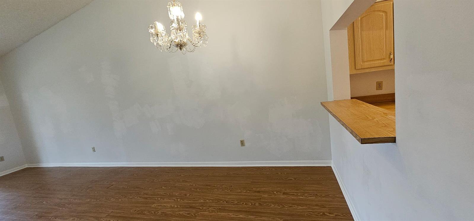 A dining area features wood-look flooring, a crystal chandelier, and a kitchen pass-through window — 7879 Willow Spring Drive # 923, Lake Worth FL 33467, LAKE WORTH, FL