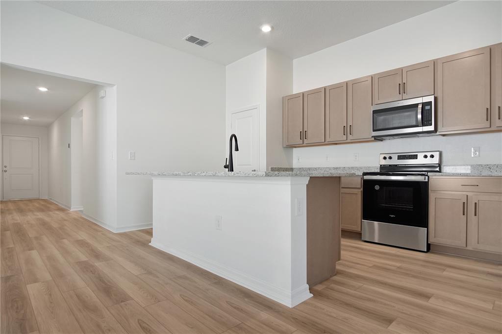 A kitchen features light wood cabinets, granite countertops, stainless steel appliances, and a central island — 9224 WESTSIDE HILLS DRIVE, DAVENPORT, FL