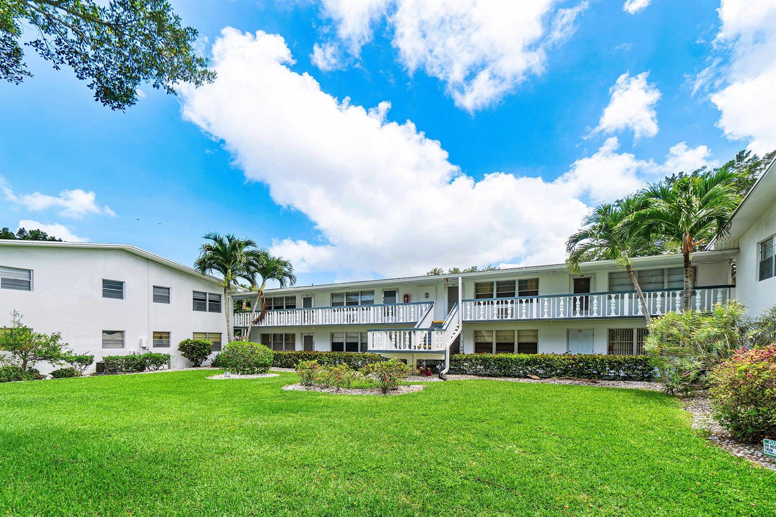 A two-story apartment building with a white exterior, balconies, and a grassy courtyard — 57 Canterbury, West Palm Beach FL 33417, WEST PALM BEACH, FL