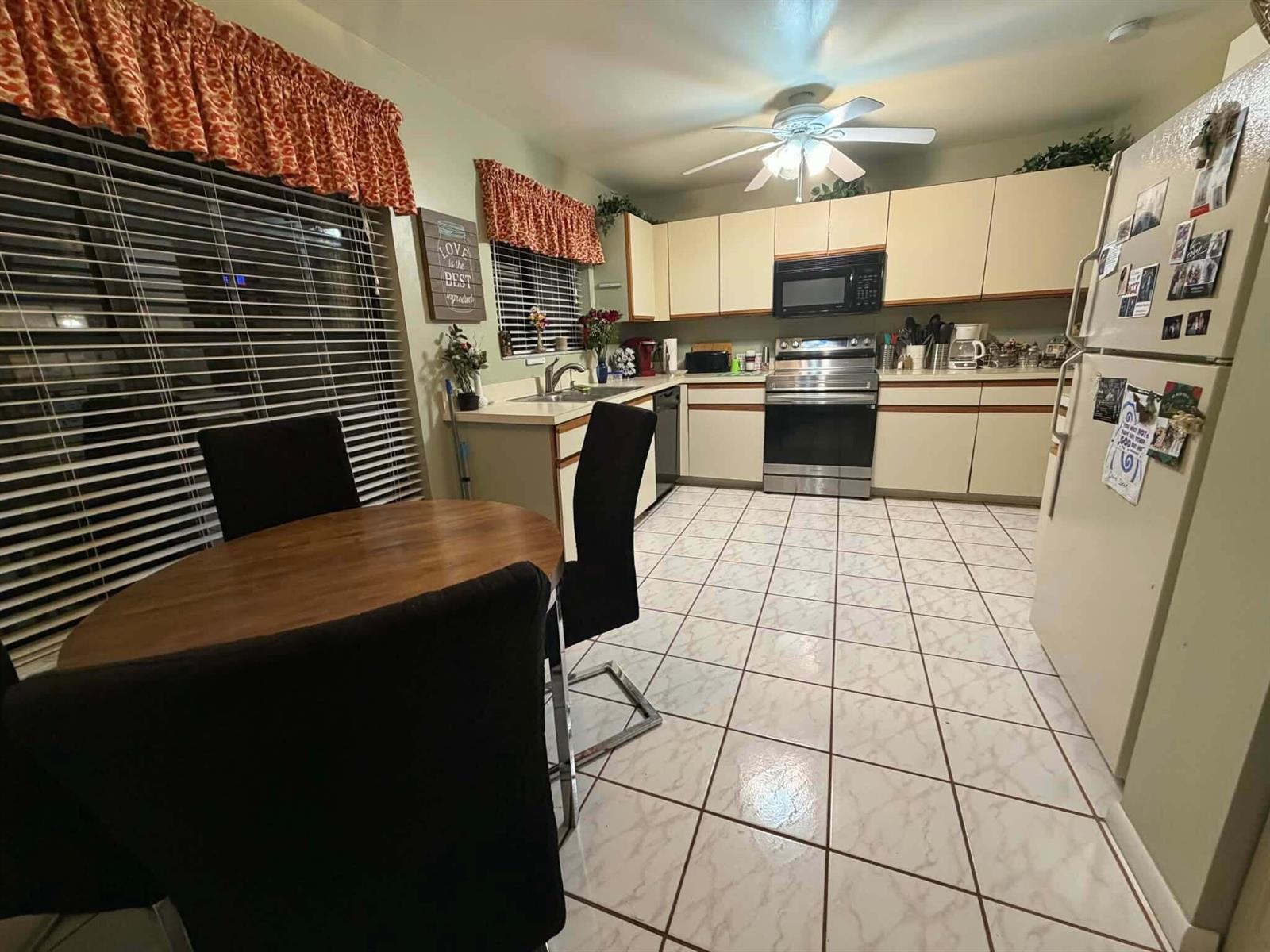 A kitchen features light-colored cabinets, stainless steel appliances, tile flooring, and a small dining area — 3209 Perimeter Drive # 2713, FL 33467, FL