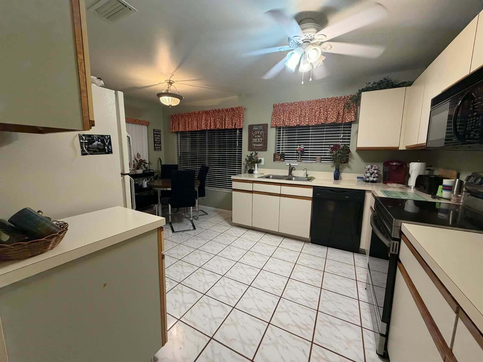 A kitchen with white cabinets, black appliances, tile flooring, and an adjacent dining area — 3209 Perimeter Drive # 2713, FL 33467, FL