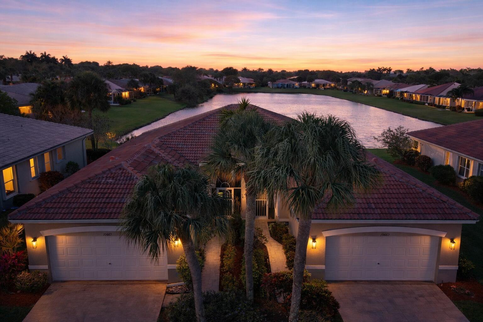 An aerial view of a residential house with a tiled roof and two garages at sunset — 10665 Royal Caribbean Circle, Boynton Beach FL 33437, BOYNTON BEACH, FL