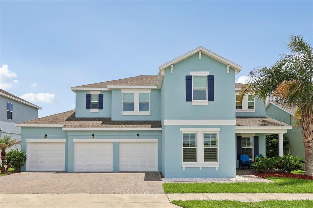 A two-story light blue house with a three-car garage and a front porch — 343 BLUE CYPRESS DRIVE, GROVELAND, FL