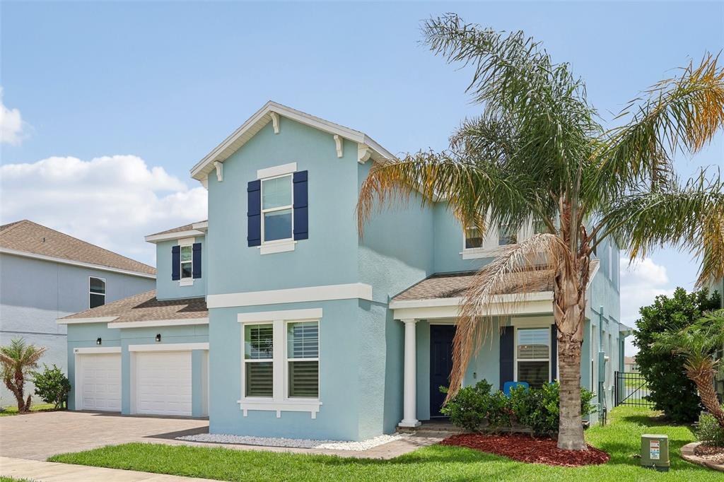 A light blue two-story house with a two-car garage and a palm tree in front — 343 BLUE CYPRESS DRIVE, GROVELAND, FL