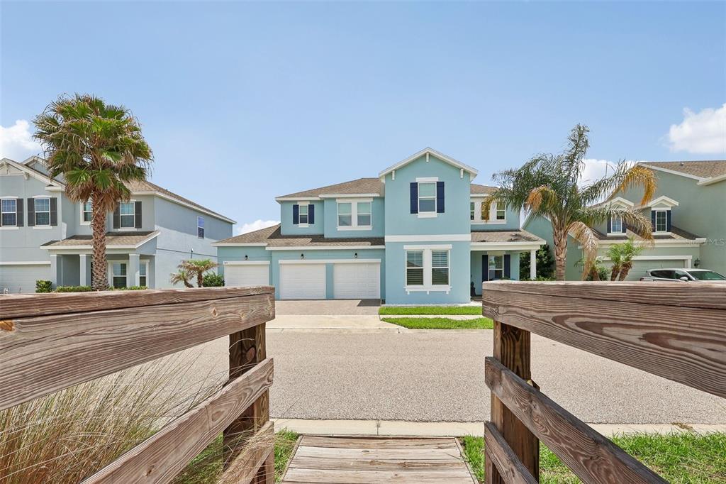 A light blue two-story house with a three-car garage viewed from a wooden bridge — 343 BLUE CYPRESS DRIVE, GROVELAND, FL
