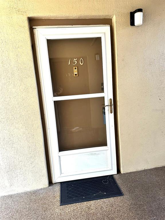 A white storm door with the number 150 is mounted on a textured beige exterior wall — 596 ORANGE DRIVE UNIT 150, ALTAMONTE SPRINGS, FL