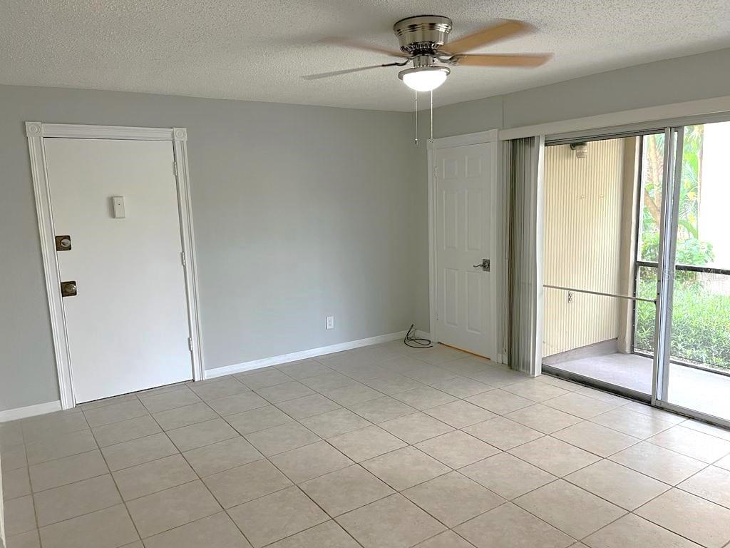 An empty room with light tile flooring, a ceiling fan, two doors, and sliding glass doors — 596 ORANGE DRIVE UNIT 150, ALTAMONTE SPRINGS, FL