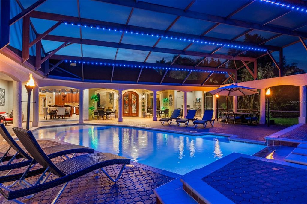 A screened-in pool area features lounge chairs, a hot tub, and blue ambient lighting — 817 HAIL COURT, PORT ORANGE, FL