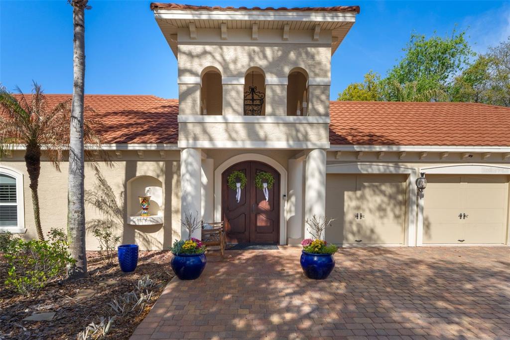 The exterior of a house features a tiled roof, a central tower, and a brick driveway — 817 HAIL COURT, PORT ORANGE, FL