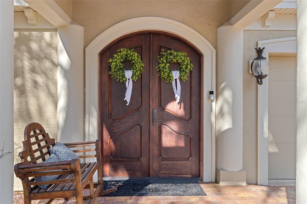 A wooden rocking chair sits on a porch in front of double arched wooden doors — 817 HAIL COURT, PORT ORANGE, FL