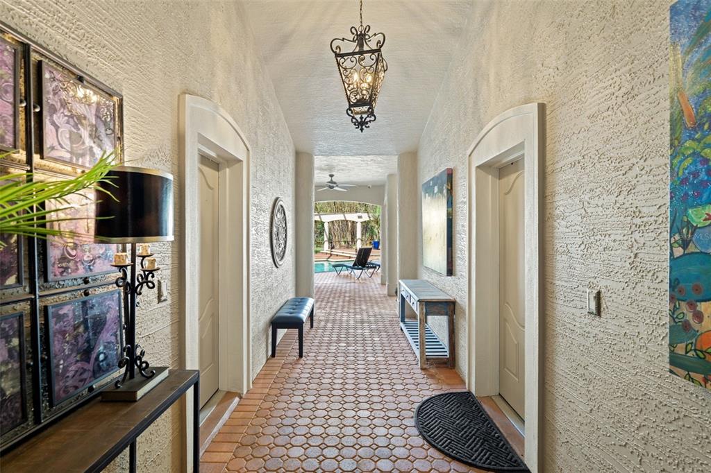 A hallway with textured walls and terracotta tile flooring leads to an outdoor pool area — 817 HAIL COURT, PORT ORANGE, FL