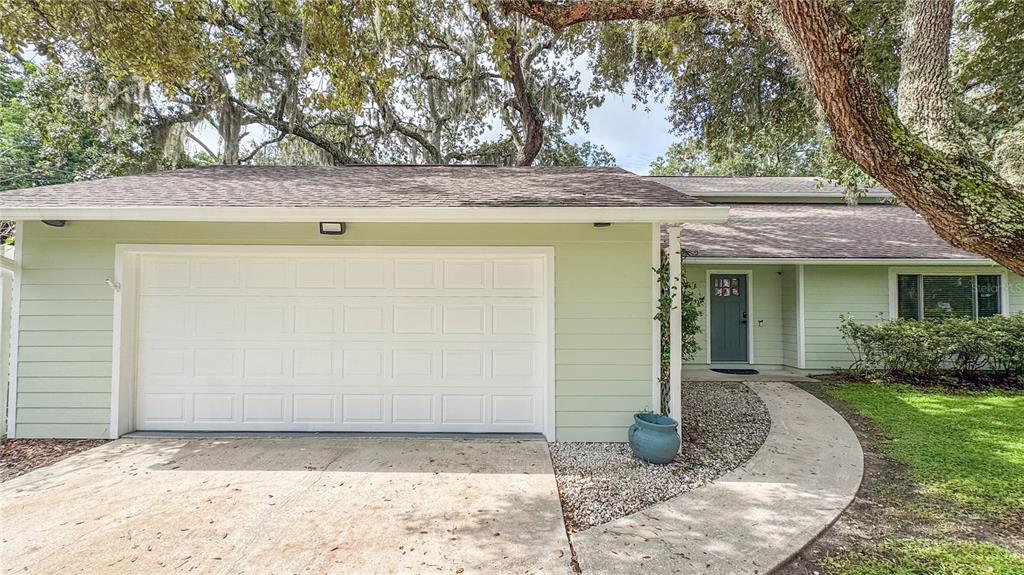 A light green house exterior features a white garage door and a front entryway — 2261 CHARLOTTE DRIVE, LONGWOOD, FL