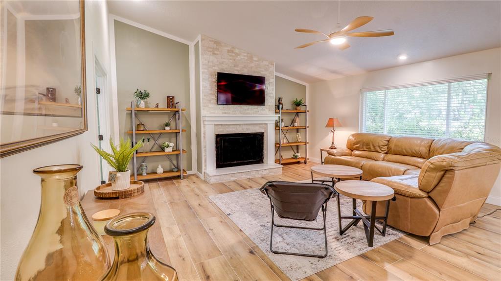 A living room features a stone fireplace, wood-look tile flooring, and a leather sectional sofa — 2261 CHARLOTTE DRIVE, LONGWOOD, FL