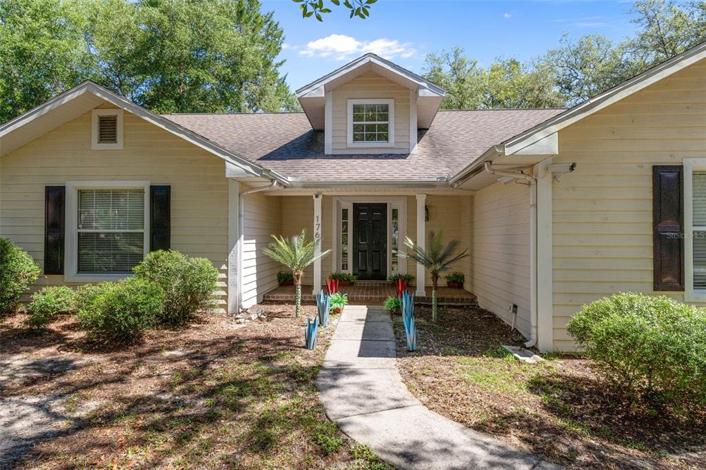 A single-story house with light yellow siding, dark shutters, and a central front entrance — 1761 E CLEVELAND STREET, HERNANDO, FL