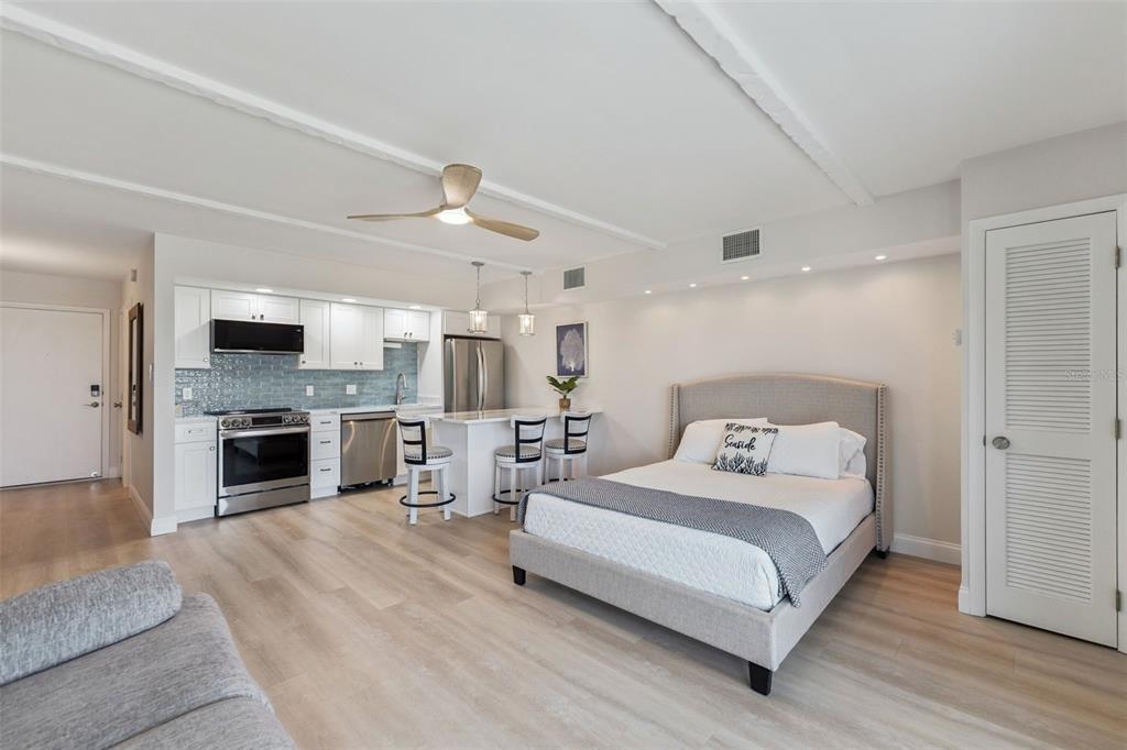 A studio apartment features a kitchen with light blue backsplash, a bed, and light flooring — 3700 S ATLANTIC AVENUE UNIT 416, NEW SMYRNA BEACH, FL