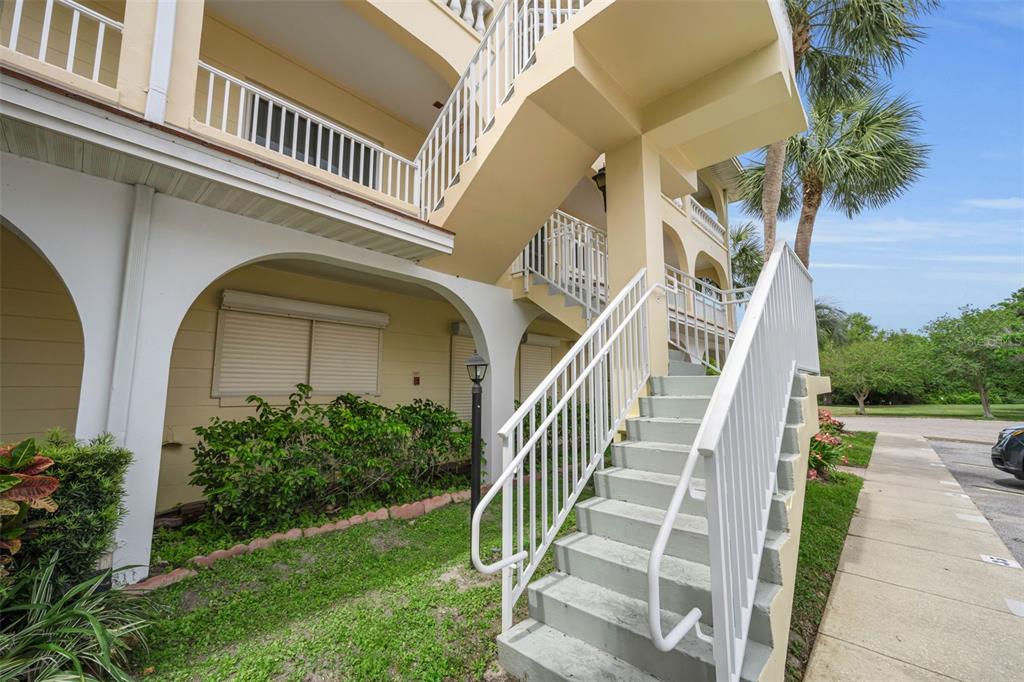 An exterior view of a multi-story building featuring concrete stairs and white metal railings — 2223 PHILIPPINE DRIVE UNIT 35, CLEARWATER, FL