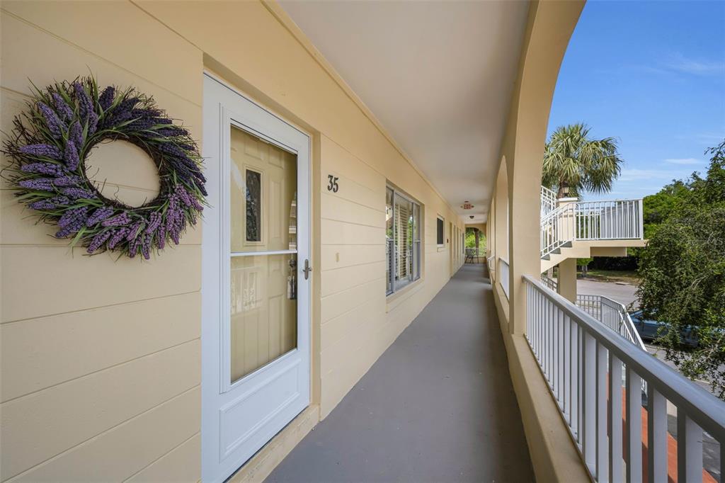 A view of an outdoor apartment walkway with a white door, number 35, and railings — 2223 PHILIPPINE DRIVE UNIT 35, CLEARWATER, FL