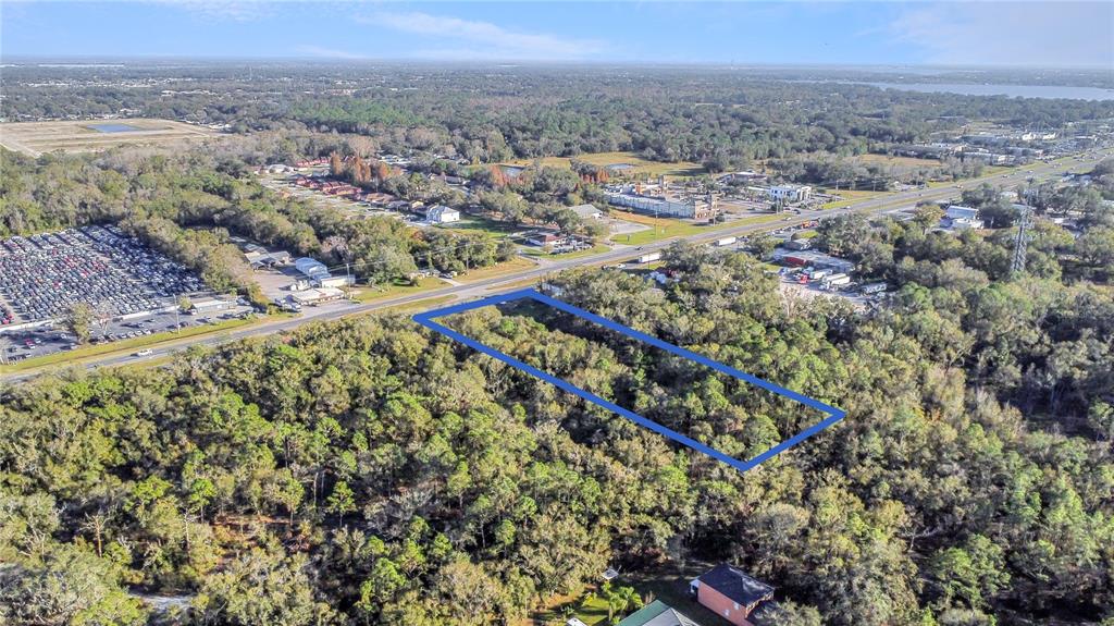 An aerial view shows a rectangular plot of land outlined in blue amidst a wooded area — 0 US-98, LAKELAND, FL