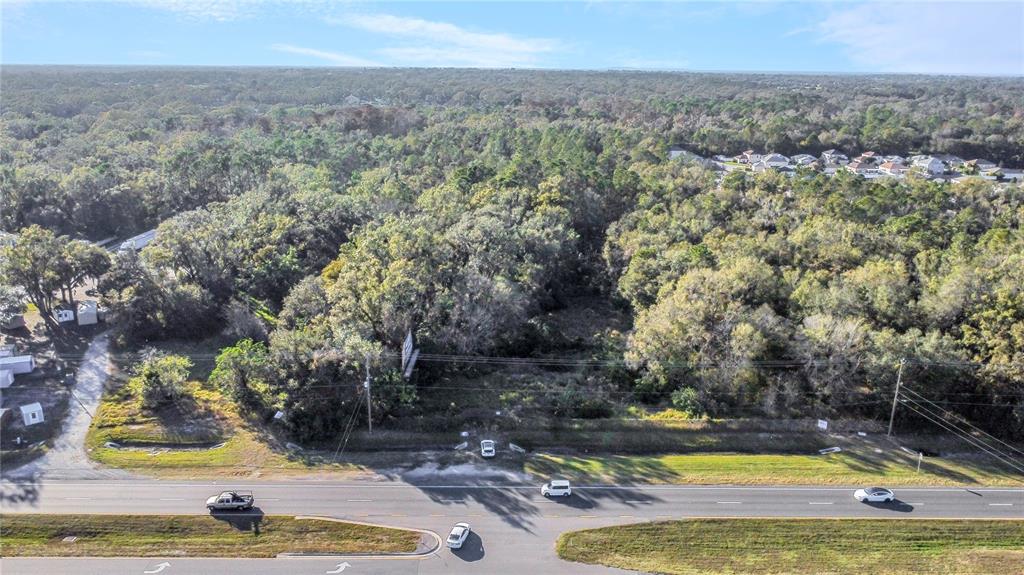 An aerial view shows a wooded, undeveloped lot situated along a multi-lane highway — 0 US-98, LAKELAND, FL