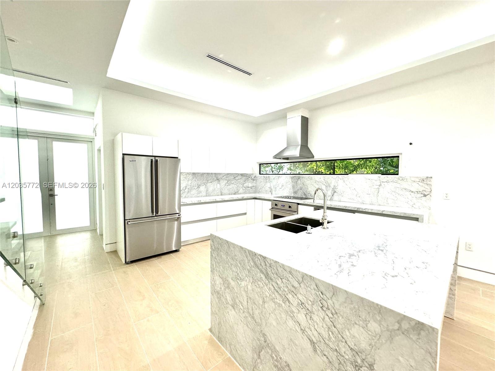 A modern kitchen features white cabinetry, marble countertops, a large island, and stainless steel appliances — 5728 NW 5th Ct # 2, Miami FL 33127, MIAMI, FL